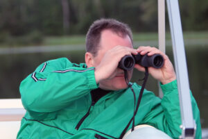 man on a boat peering through binoculars