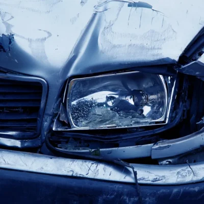 image of a car crash focused on a broken bumper of a blue car in the rain